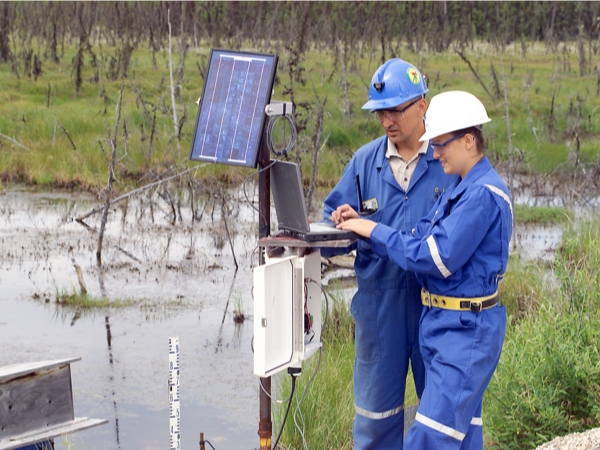 man and woman in hardhats doing tests near water